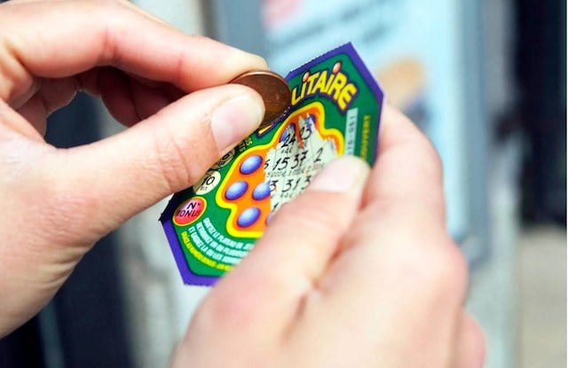 Un uomo che gratta a un gioco di gratta e vinci