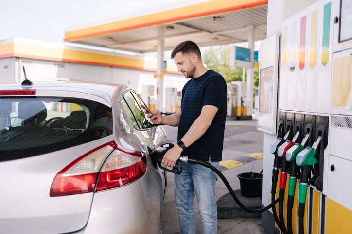 Un uomo usa il suo smartphone mentre fa benzina