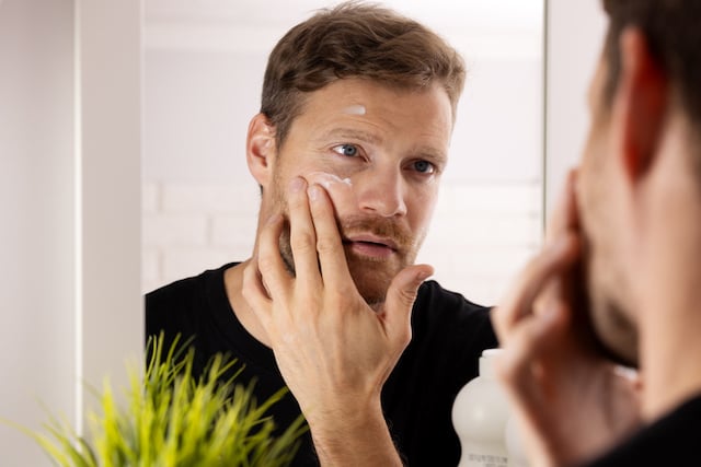 Un uomo che si spalma la crema sul viso