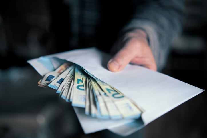 Un uomo tiene in mano una busta piena di banconote