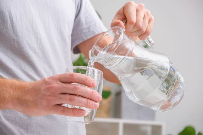 Un uomo si versa un bicchiere d'acqua