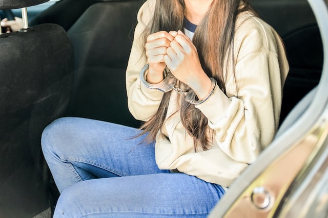 Una giovane donna ammanettata, seduta in un'auto