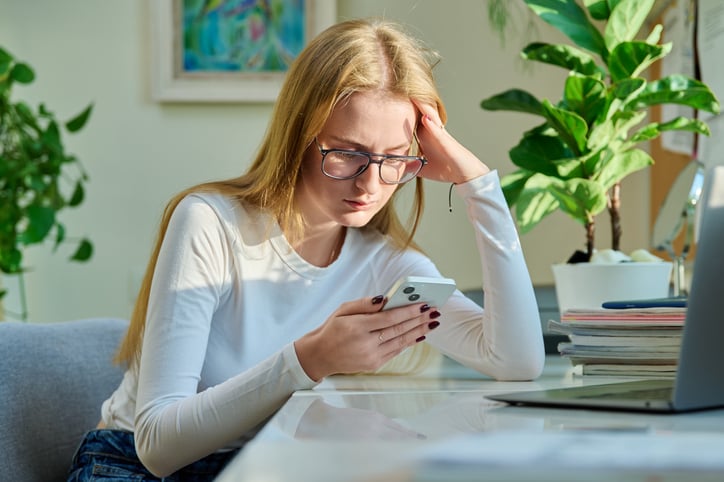 Una giovane donna triste davanti al suo smartphone