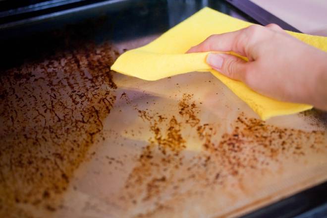 Donna che pulisce il forno con un panno