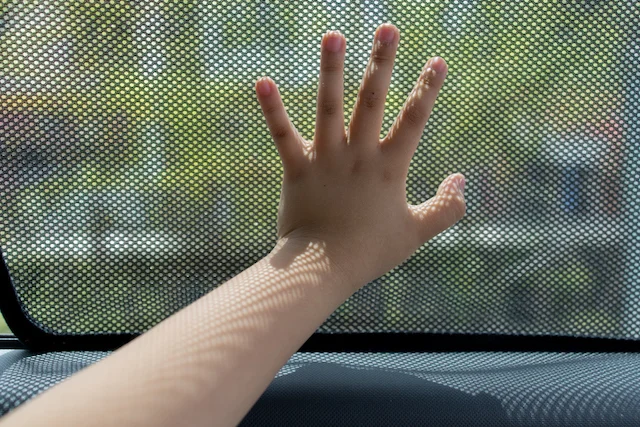 La mano di un bambino sul finestrino di un'auto
