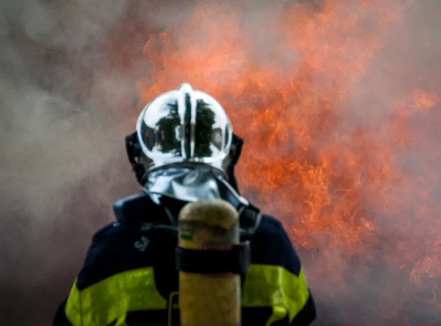Un pompiere in piedi davanti alle fiamme
