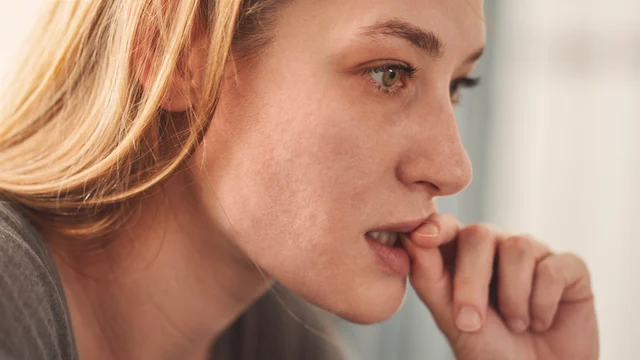 Una donna che si mangia nervosamente le unghie
