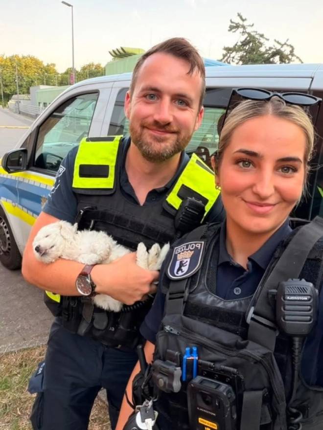 Due agenti di polizia di Berlino tengono in braccio un cucciolo