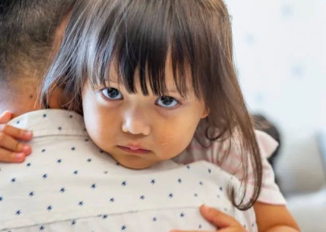 Una bambina di origine asiatica tra le braccia di suo padre