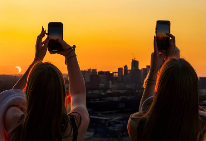 Ragazze che fotografano un'eclissi solare parziale sopra la Torre Eiffel
