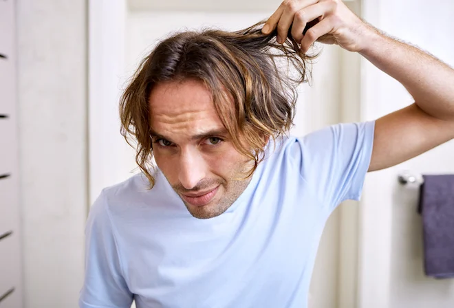 Un uomo si controlla i capelli