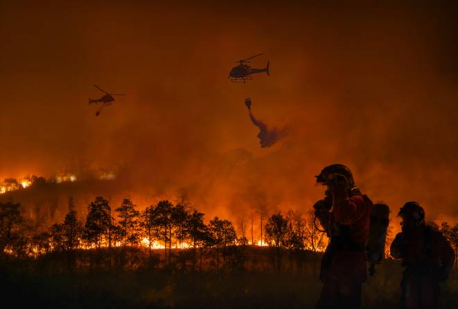 Vigili del fuoco ed elicotteri che combattono gli incendi boschivi