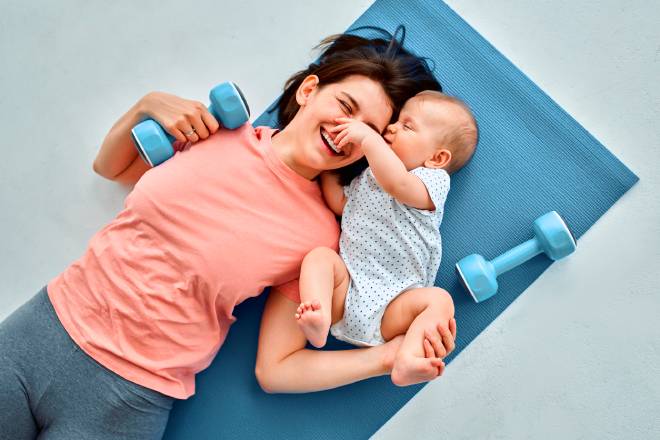 Una madre e il suo bambino su un tappetino sportivo e con manubri