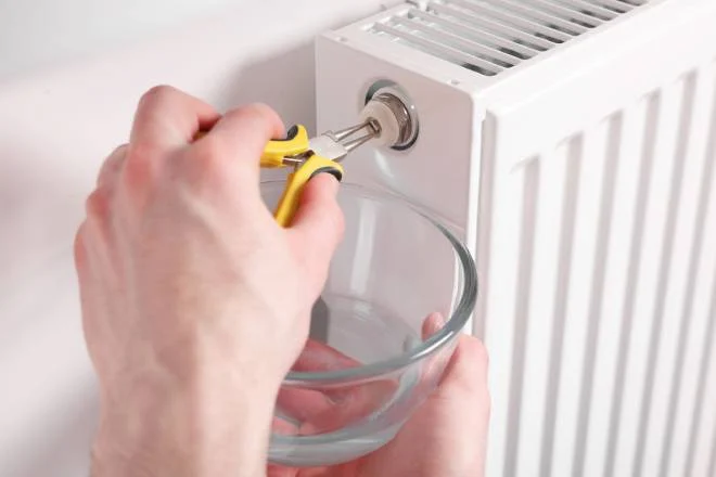 Persona che ripara un radiatore con una pinza